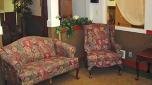 A living area with a floral-patterned loveseat and armchair, and a decorative plant in the background